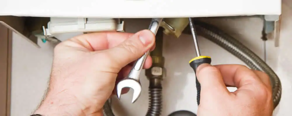 Boiler repair technician tightening pipe fittings and connections in San Francisco, CA