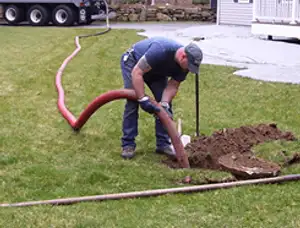 Septic pumping technician servicing a residential septic tank with a vacuum hose in San Francisco, CA