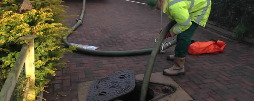 Septic tank cleaning technician servicing a septic tank with a vacuum hose in San Francisco, CA