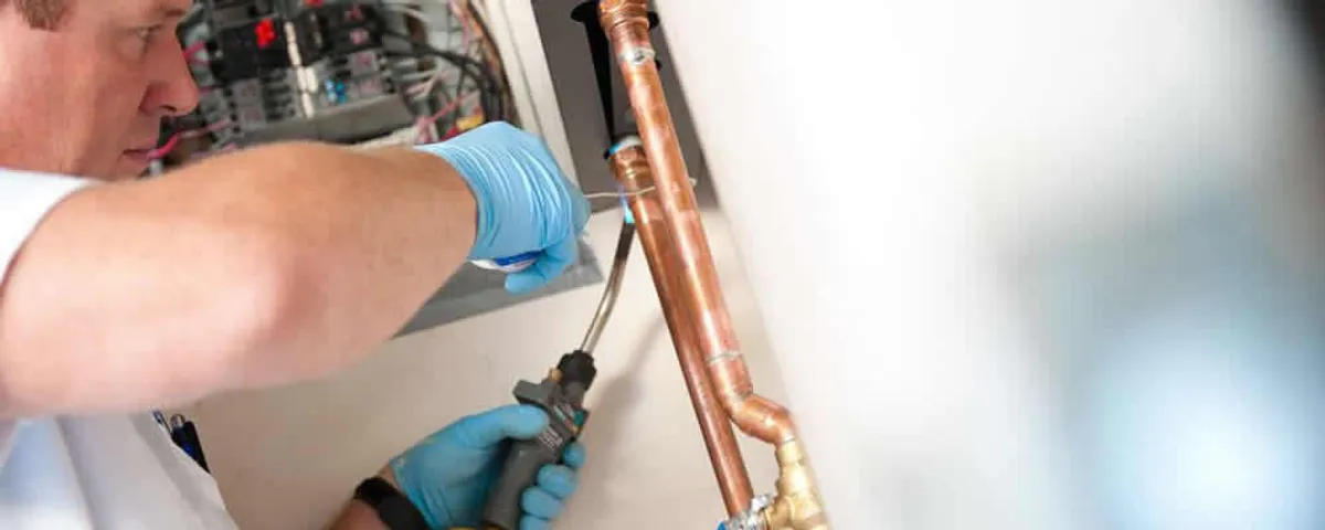 Water heater repair technician testing copper pipe connections and controls in San Francisco, CA