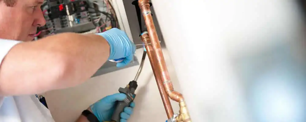 Water heater repair technician testing copper pipe connections and controls in San Francisco, CA